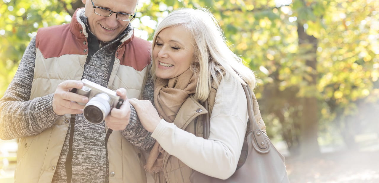 A man and woman smile and look at photos on a digital camera together. 