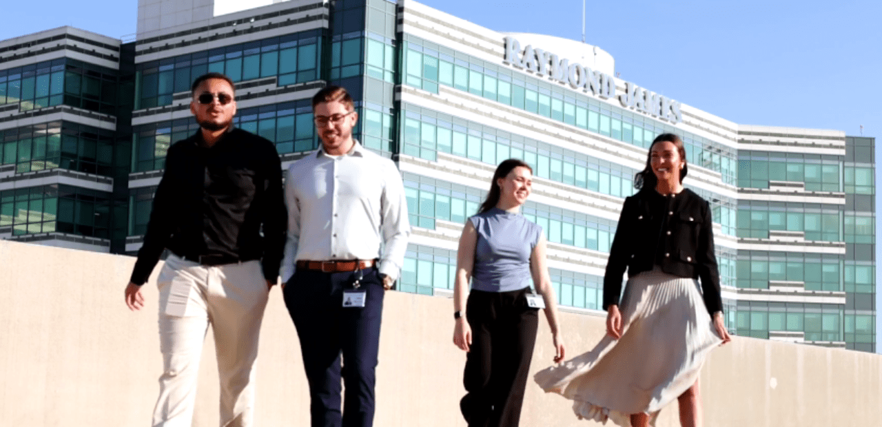 four associates walking with the Raymond James building in the background